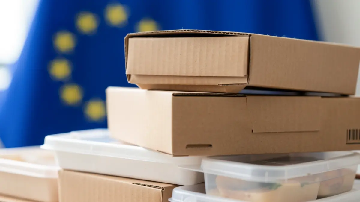 Imagem genérica de embalagens de alimentos com bandeira da União Europeia ao fundo.