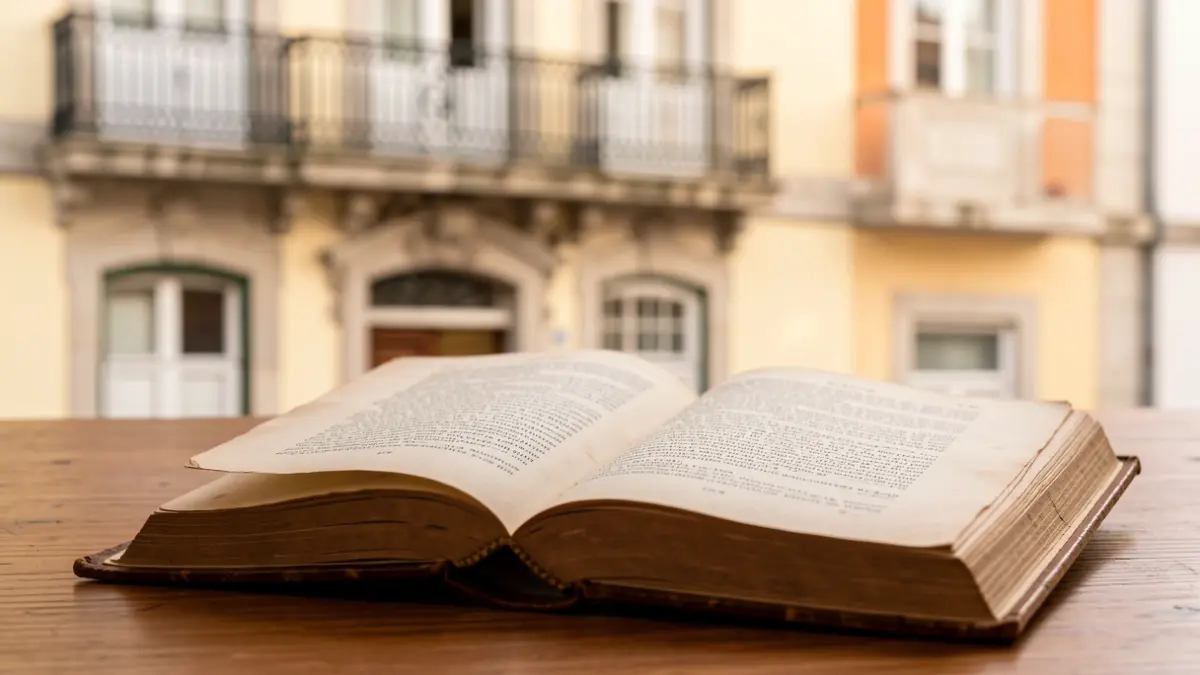 Imagen de un libro abierto sobre un escritorio, con un edificio portugués al fondo.
