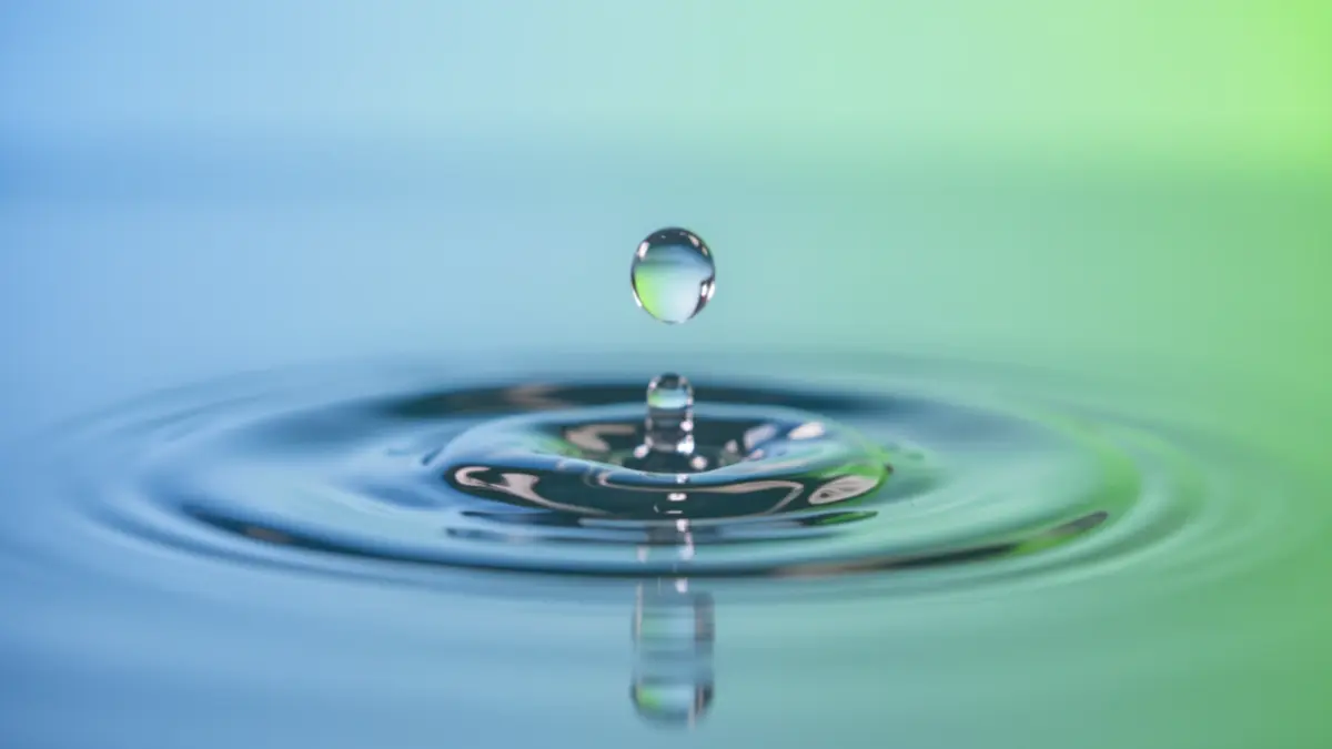Clear water droplets falling into pure water, with a subtle blue and green gradient background.