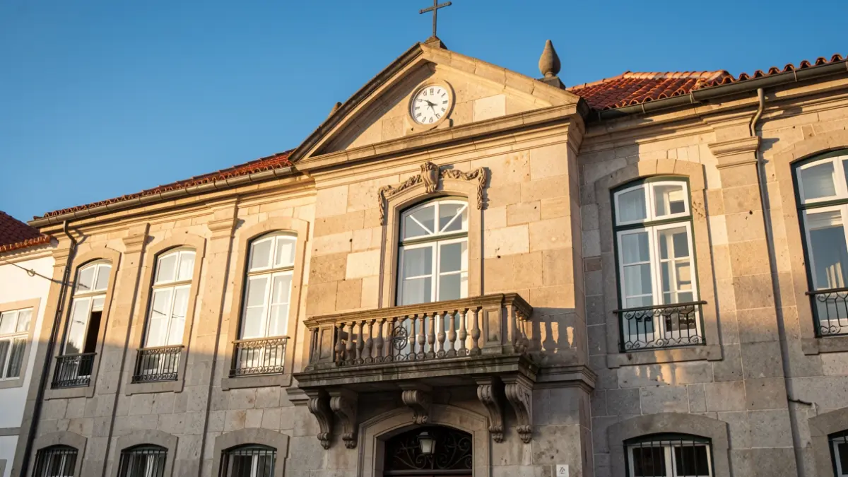 Generic image of a Portuguese town hall facade with traditional stone architecture and an ornate balcony, under the warm late afternoon light.