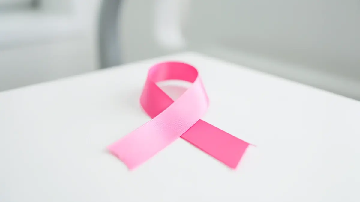 Imagen genérica de un lazo rosa de concienciación sobre el cáncer de mama sobre una superficie blanca.