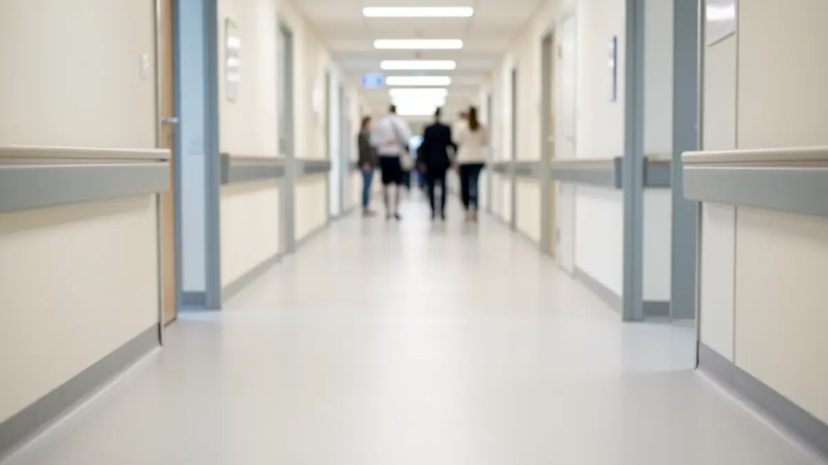 Imagem genérica de um corredor de hospital moderno com iluminação suave e difusa, focando no chão limpo e paredes desfocadas.