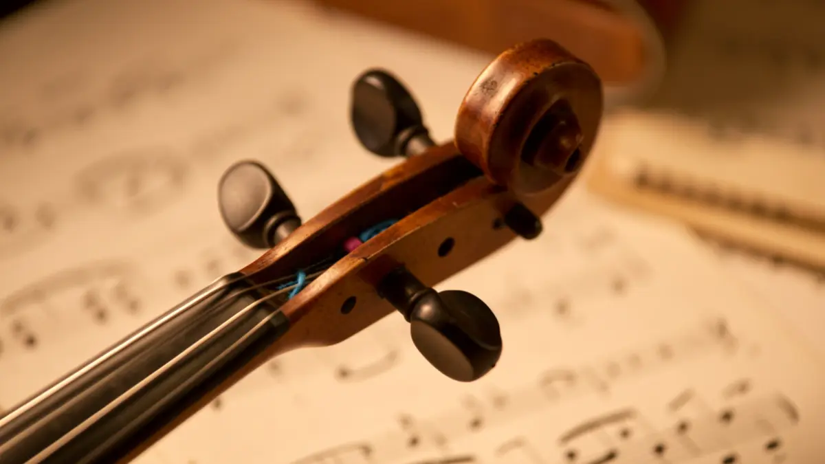 Imagem genérica de um detalhe de violino com partitura desfocada ao fundo.