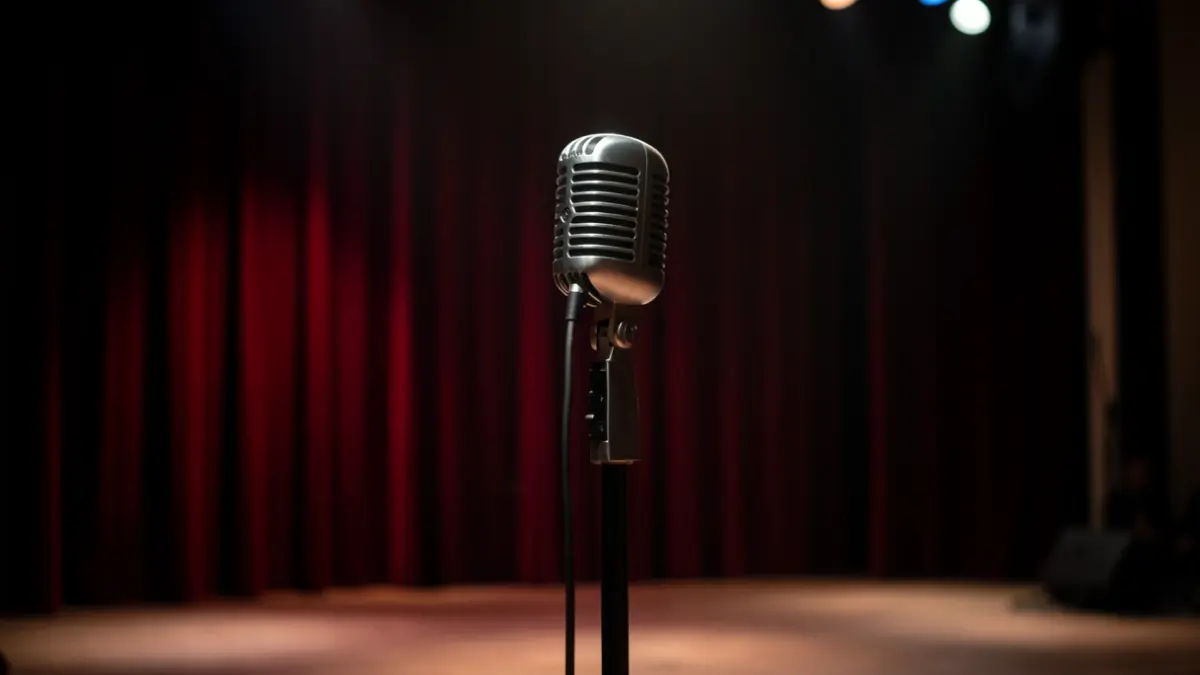 Generic image of a concert stage with a vintage microphone, soft lighting, and blurred velvet curtains.